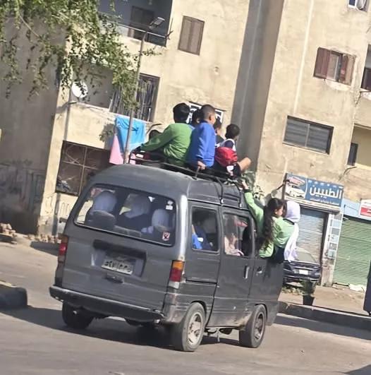 أطفال فوق سقف سيارة سوزوكي وعلى جوانبها في مدينة النهضة