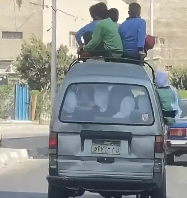 أطفال فوق سقف سيارة سوزوكي وعلى جوانبها في مدينة النهضة